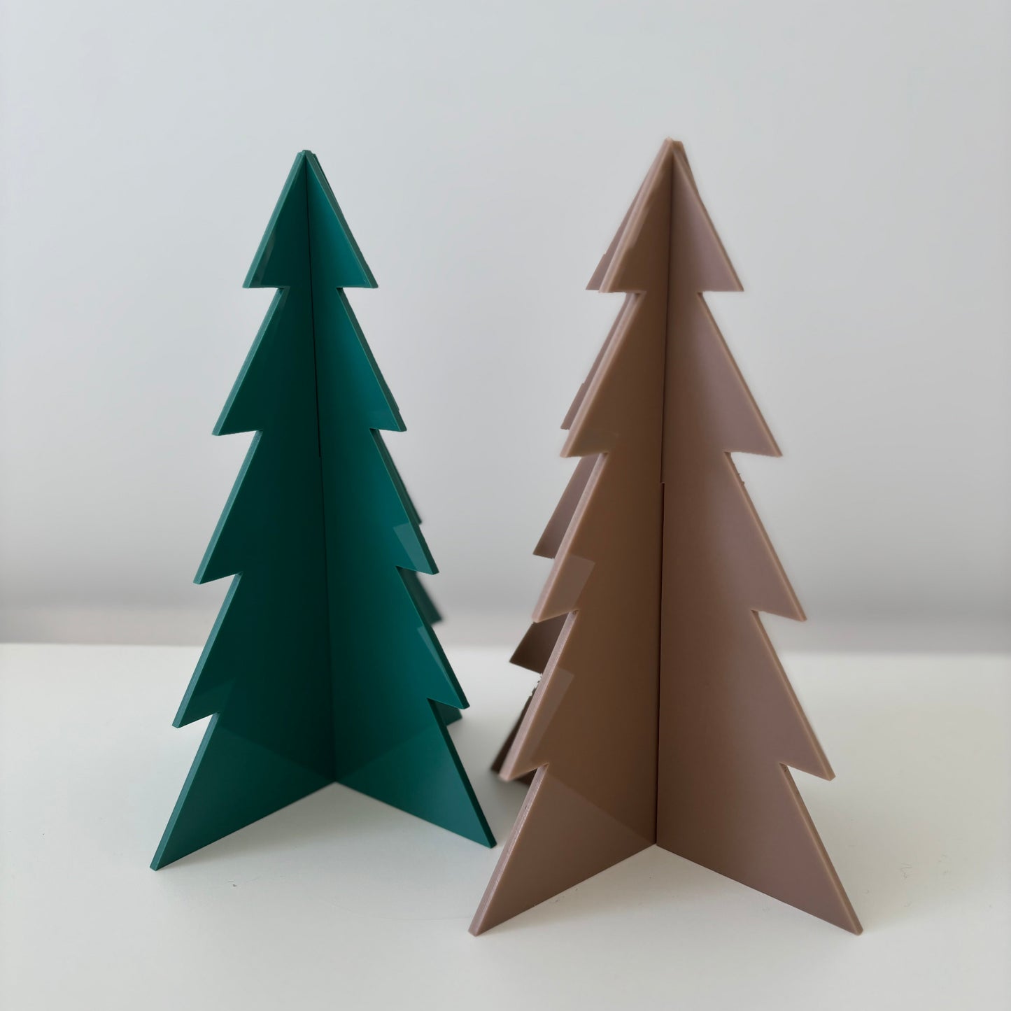 Two decorative Christmas trees, one green and one brown, on a white background.