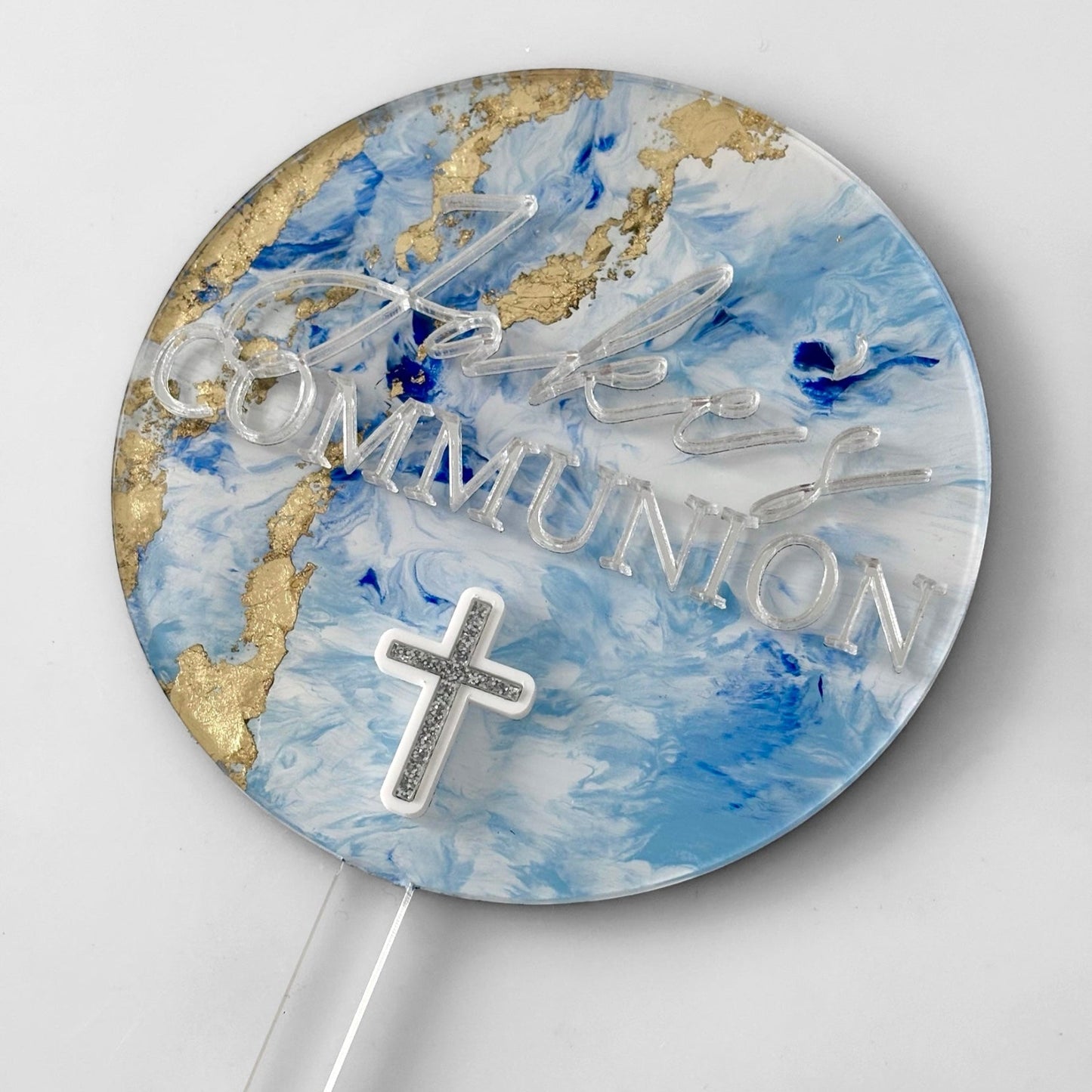 'Jake's Communion' text on a blue and silver cake topper with a white