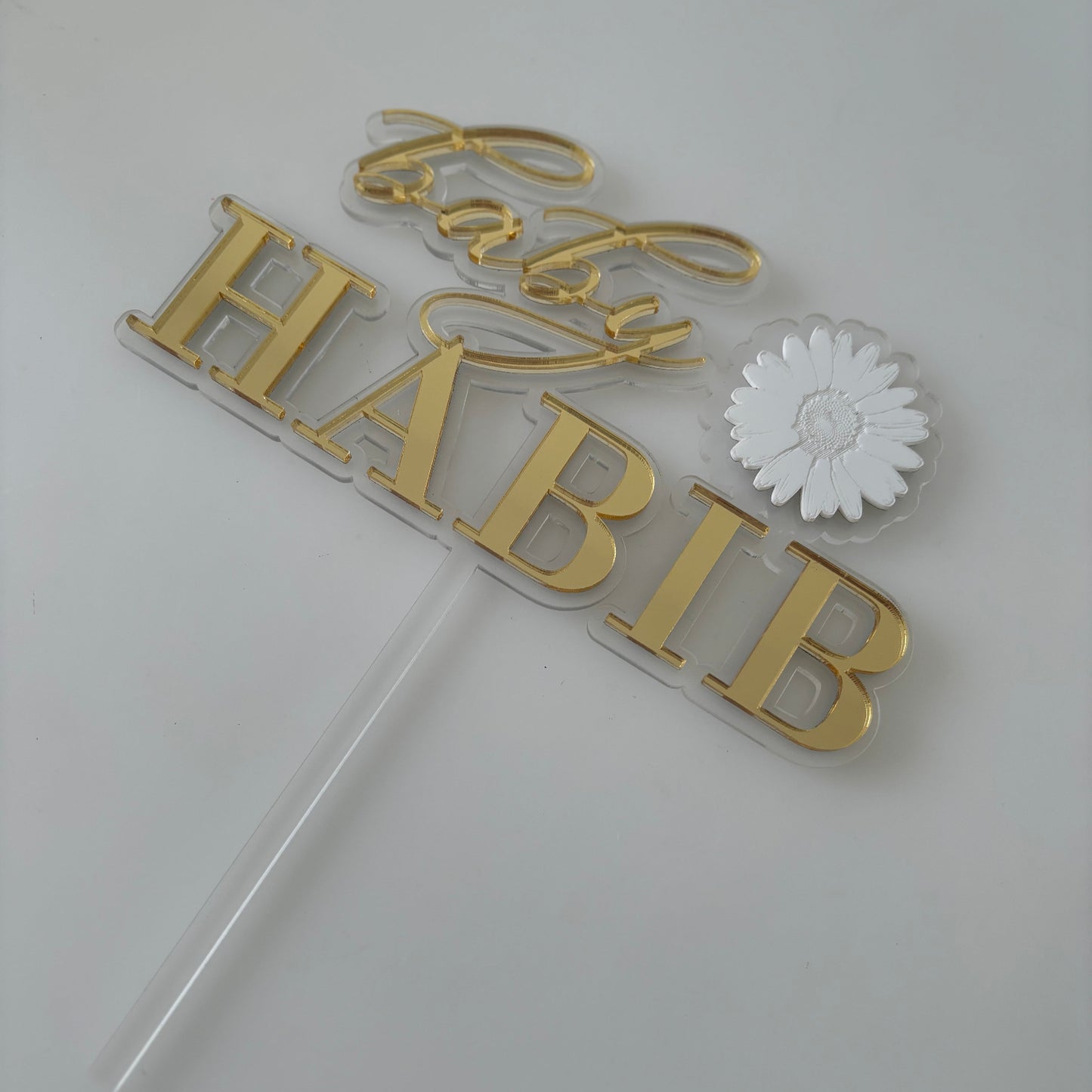 Gold personalised baby shower cake topper with a white flower.