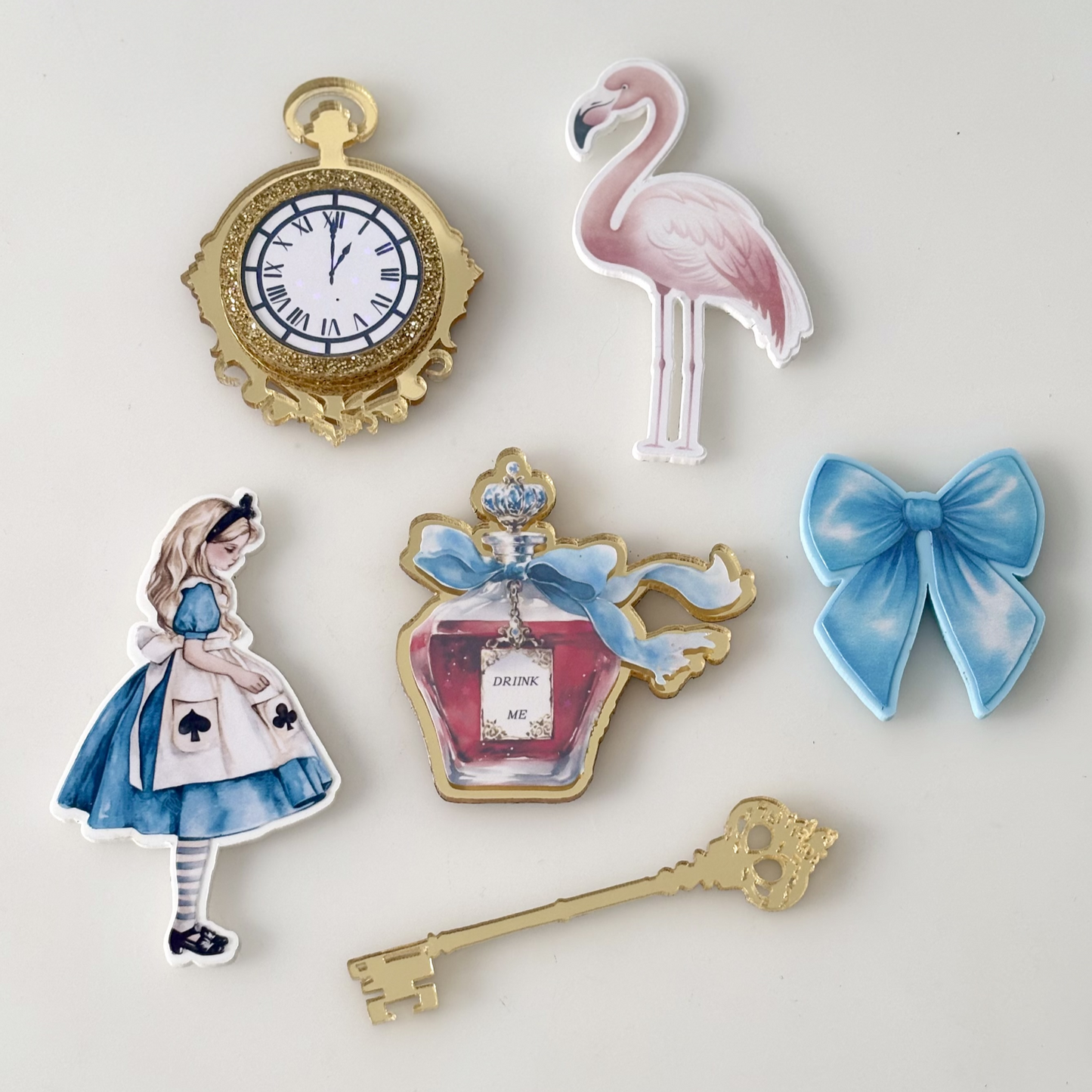 Set of decorative cake froppers including a clock, flamingo, bow, and key on a light gray background