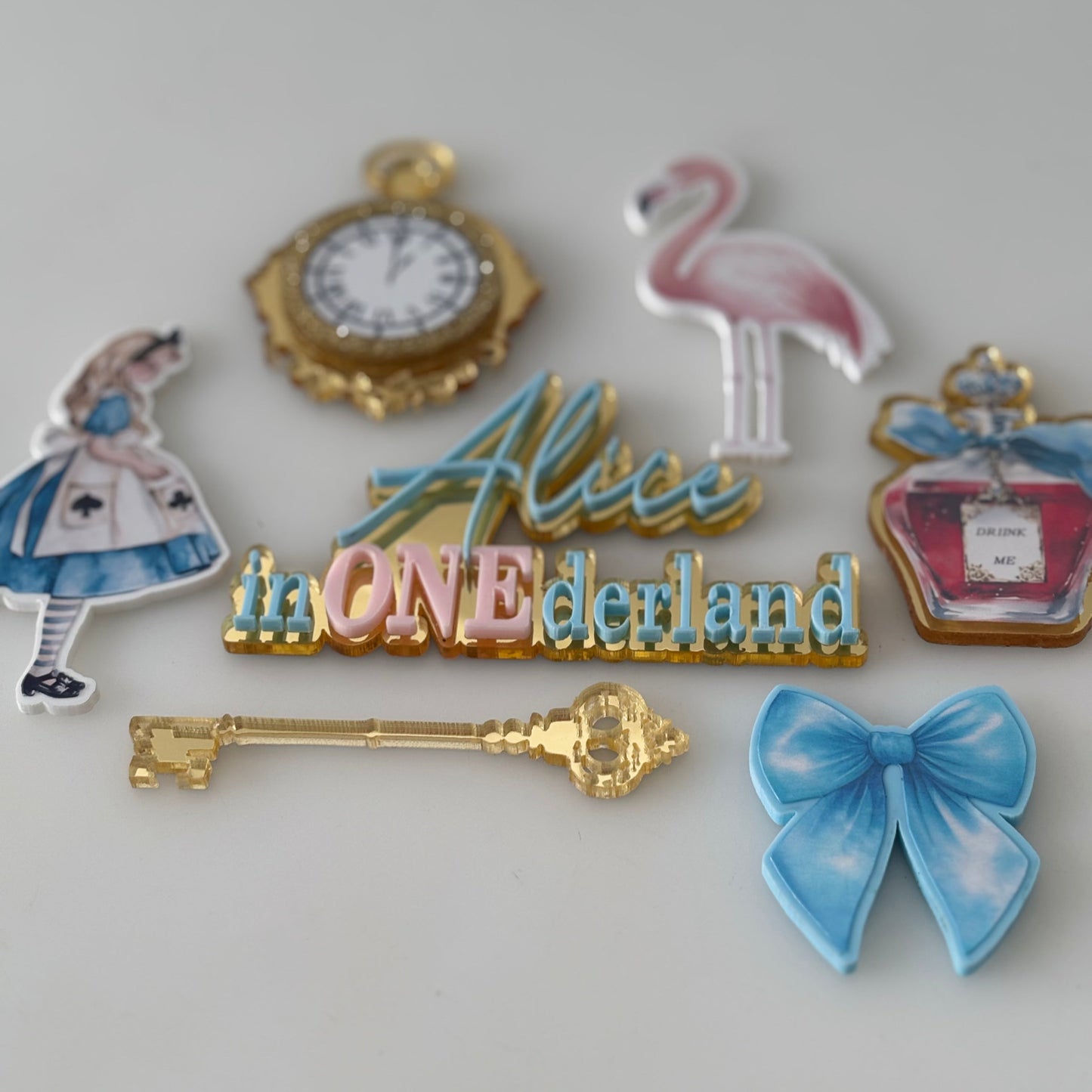 Set of decorative cake toppers including a clock, flamingo, golden key, and bow on a white background.