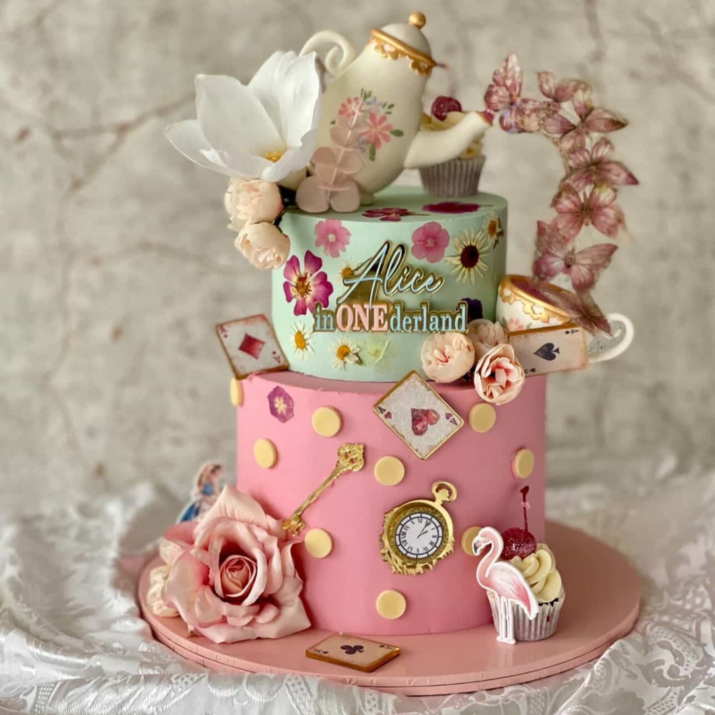 Alice In Wonderland Decorative cake with floral elements and a teapot on a textured surface