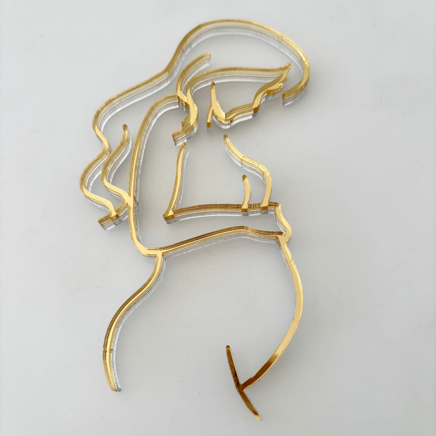 Gold line art cake topper of a pregnant woman in gold acrylic.
