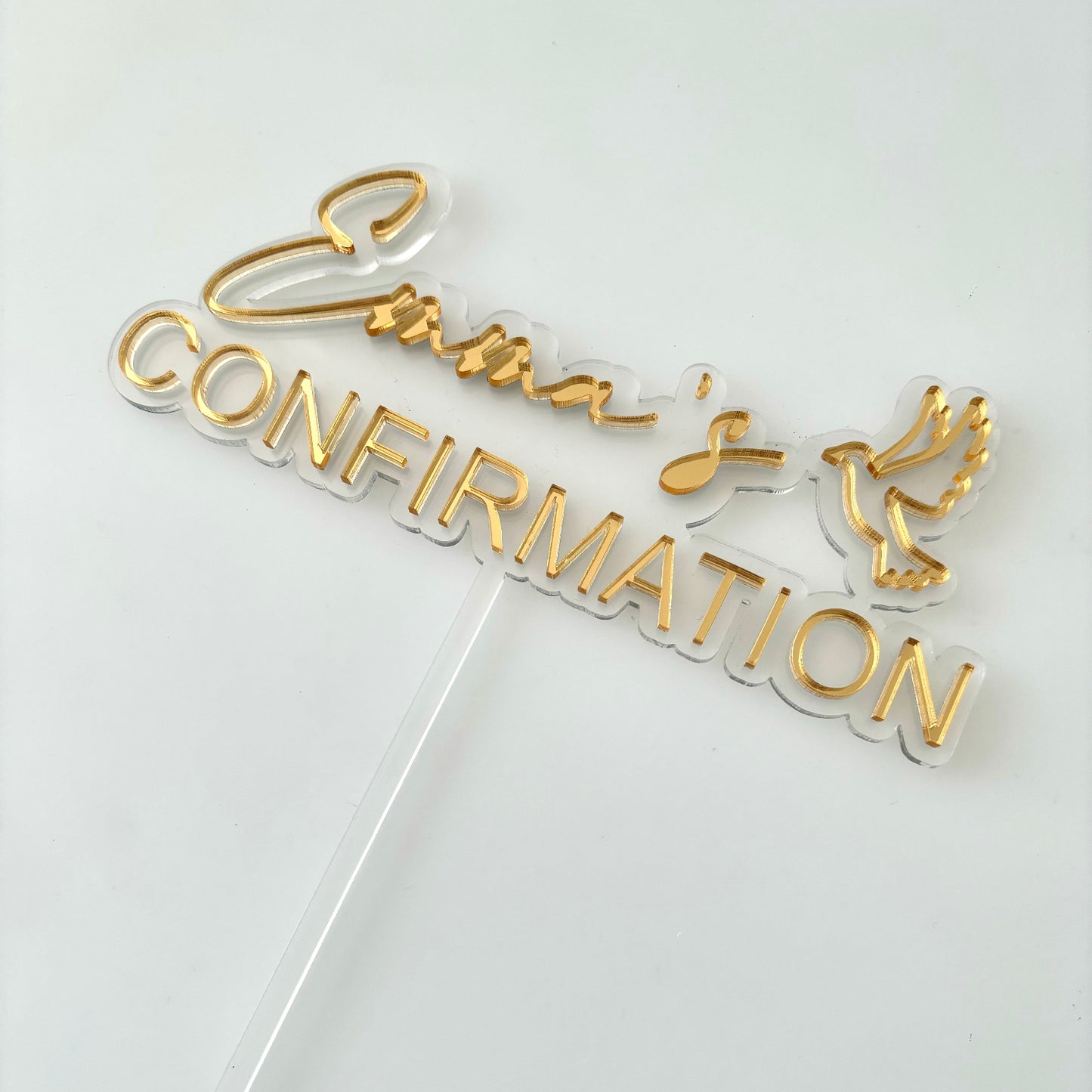Gold 'Confirmation' cake topper on a white background
