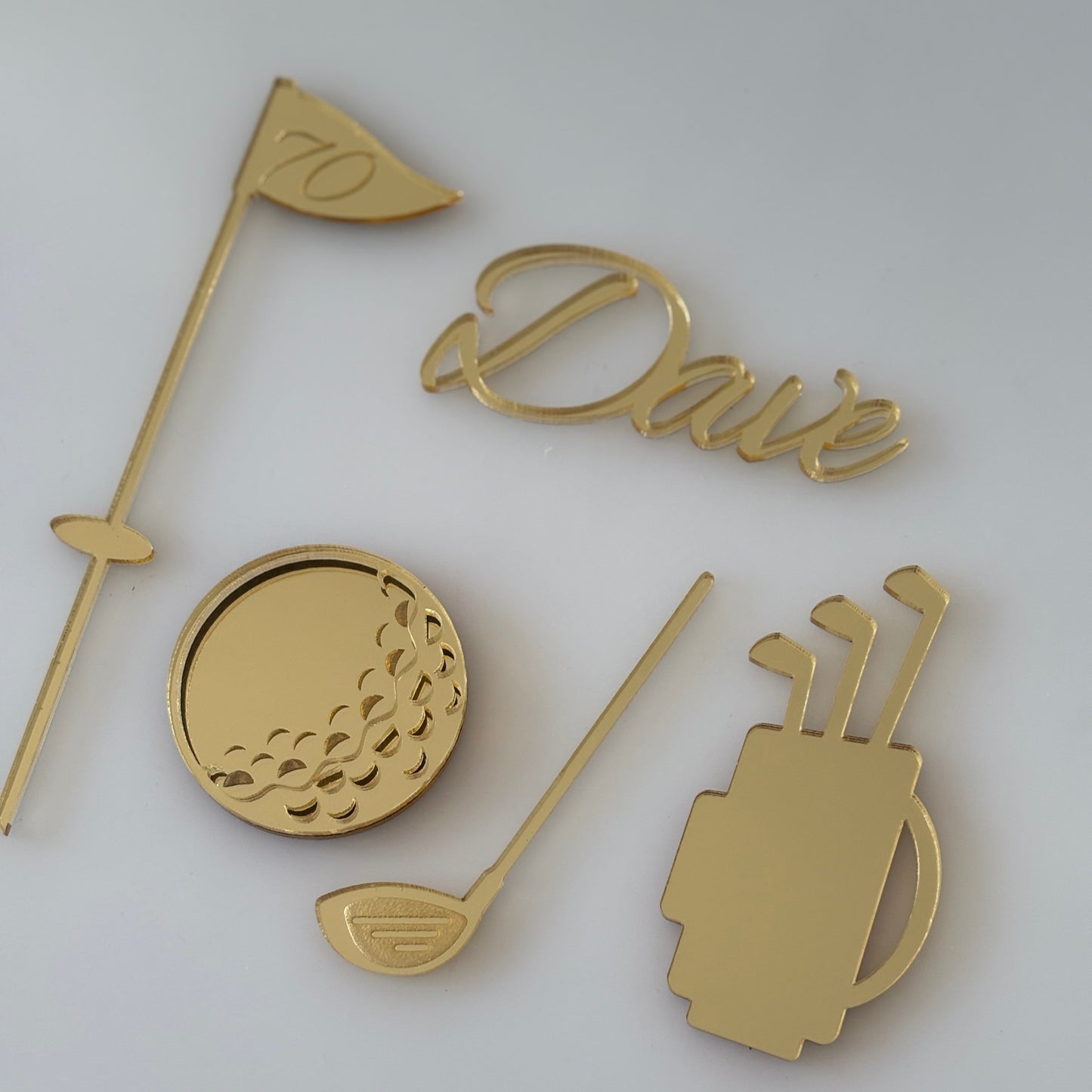 Gold-coloured golf-themed cake topper set on a white background
