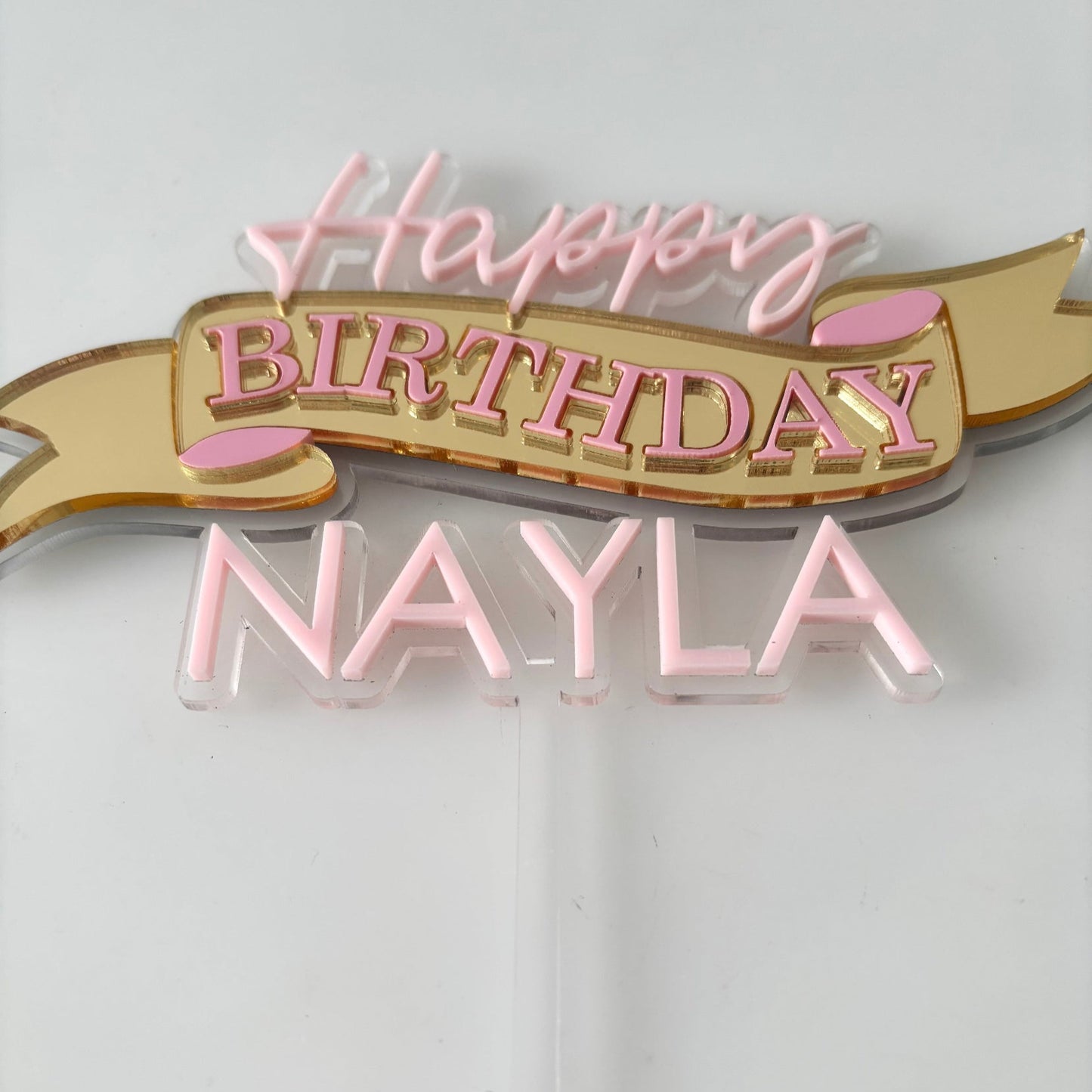 Decorative cake topper with 'Happy Birthday Nayla' text on a white background