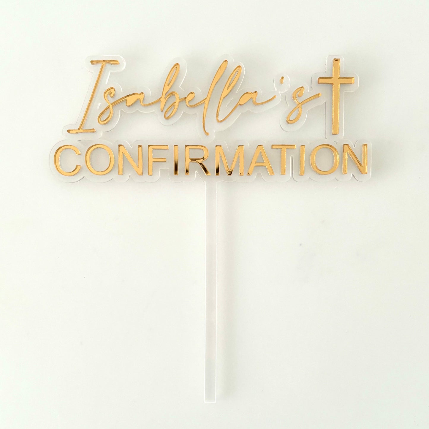 Gold 'Isabella's Confirmation' cake topper with acrylic text on a white background