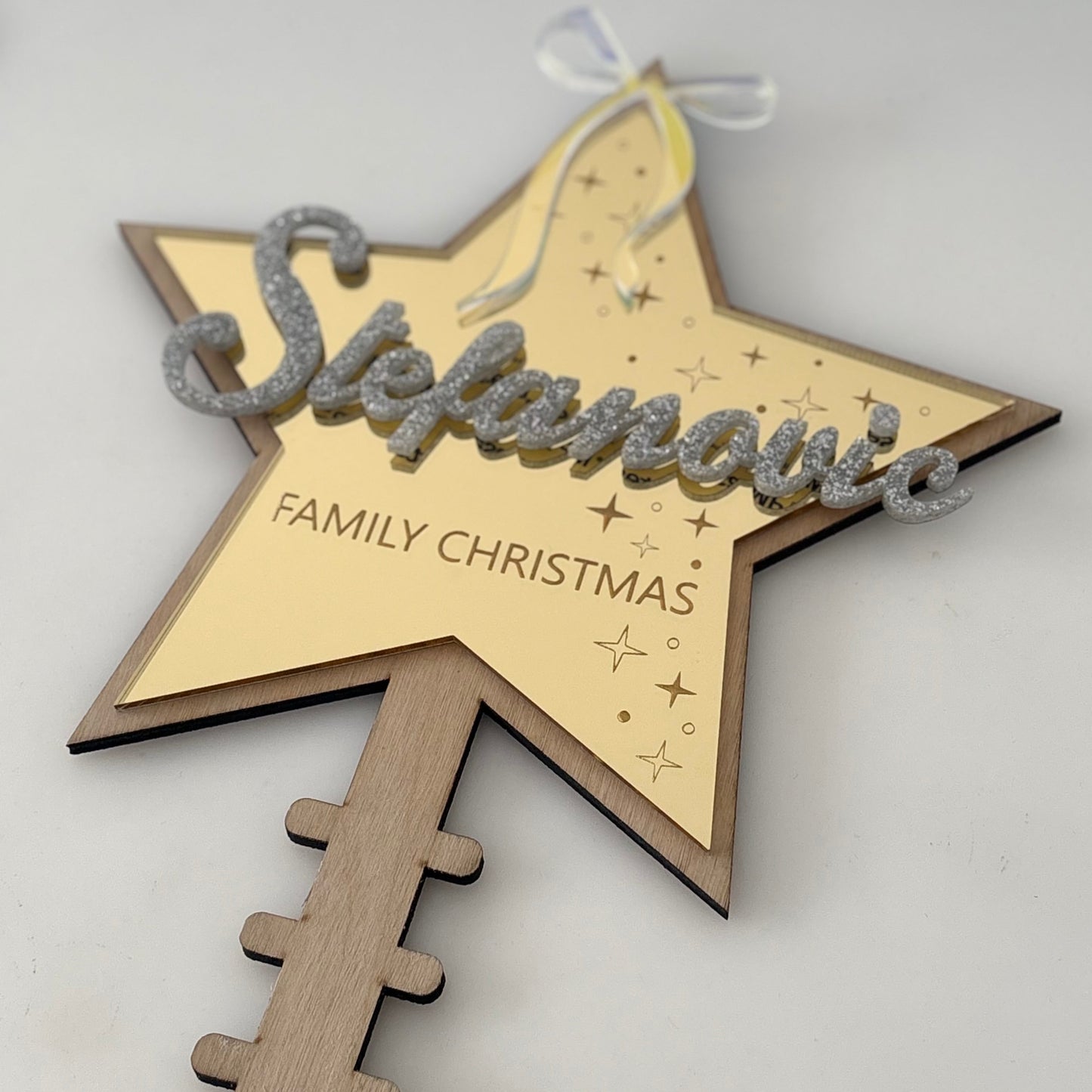 Wooden star-shaped ornament with 'Stefanovic Family Christmas' text on a light background