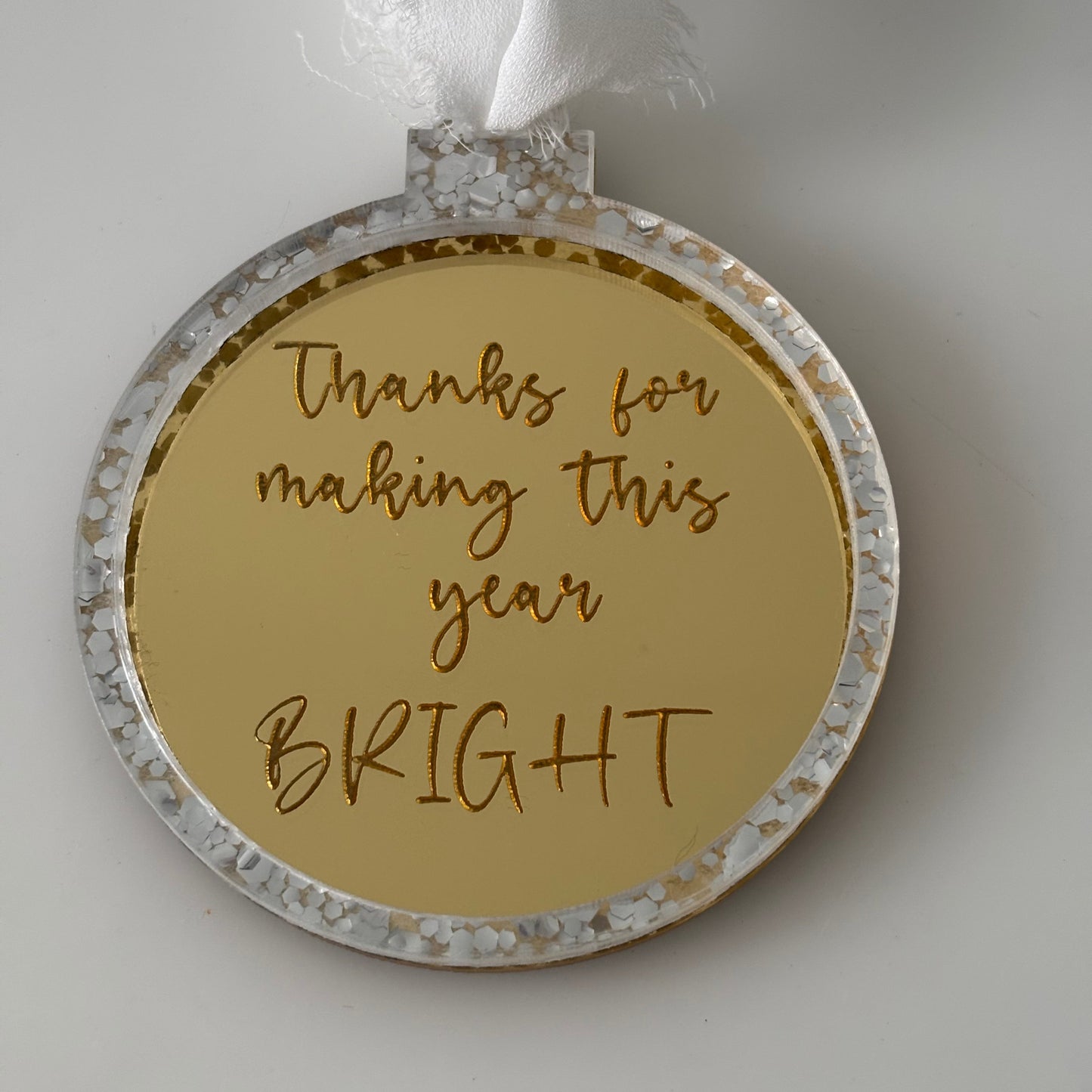 Round gold Christmas bauble with engraved text on a white background