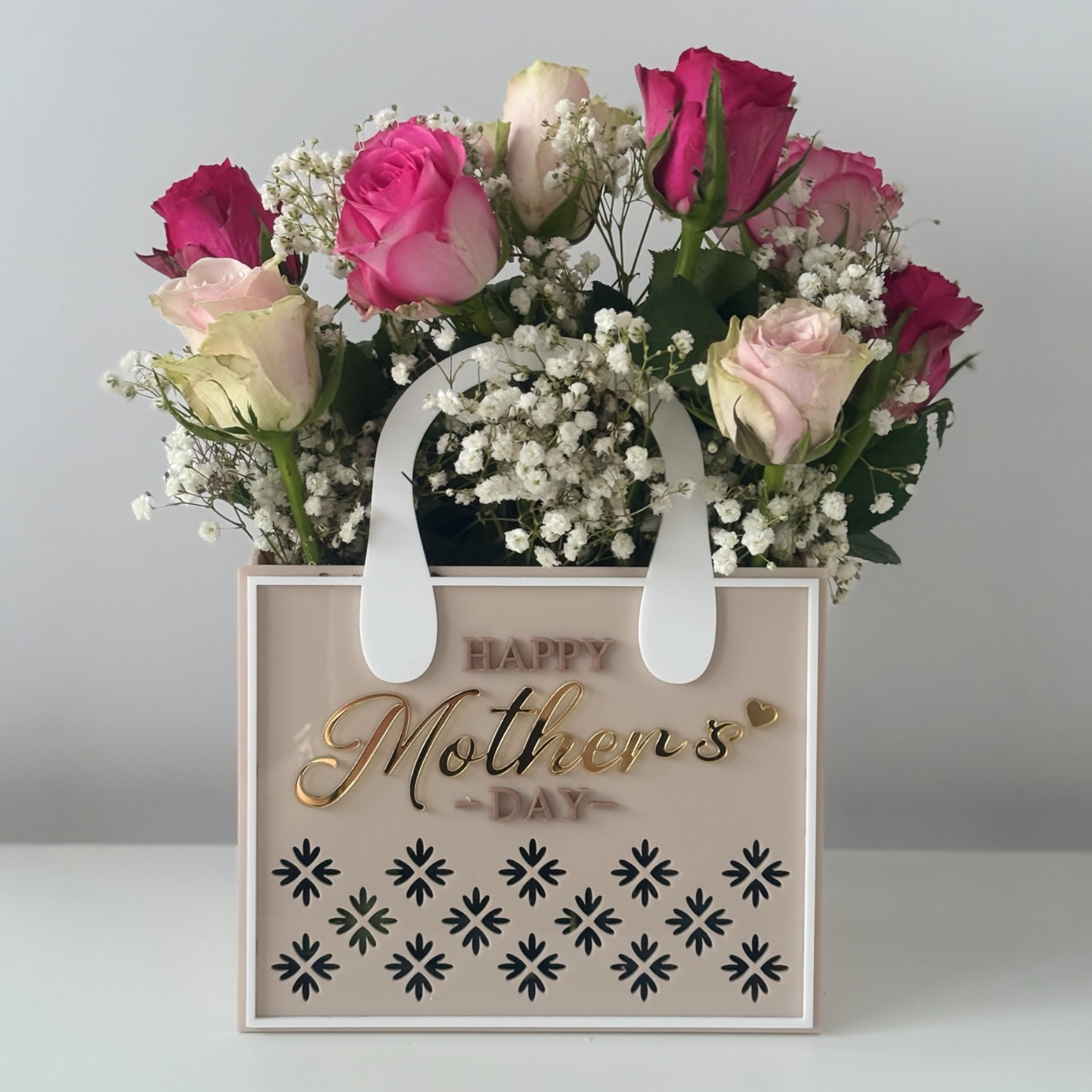 Floral arrangement in a 'Happy Mother's Day' gift bag on a light background
