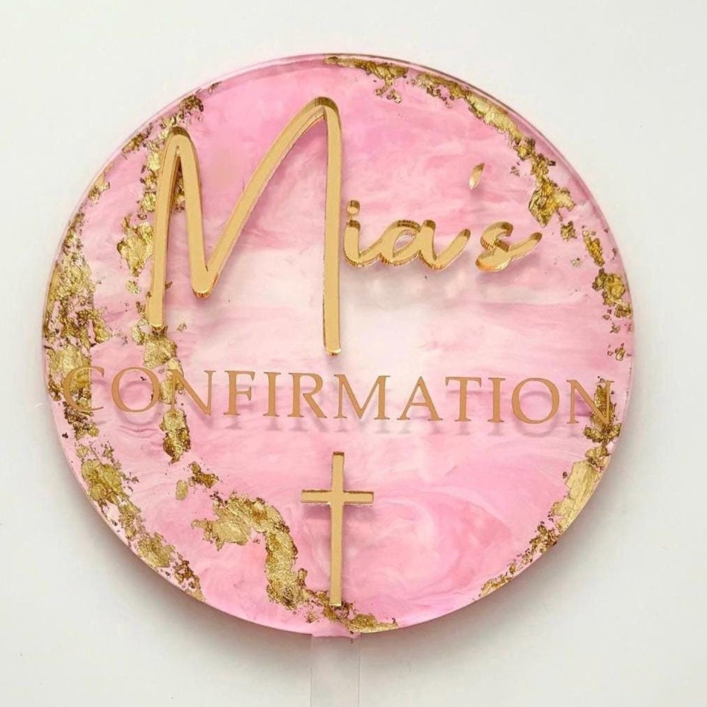 'Mia's Confirmation' text on a pink and gold cake topper with a white background