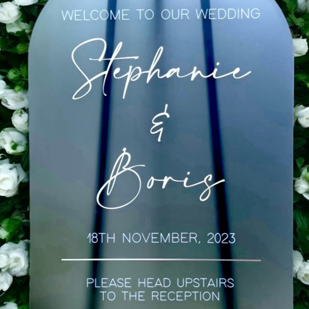 Wedding welcome sign with 'Stephanie & Boris' and date, surrounded by white flowers.