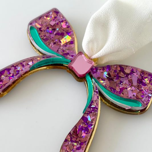 Glittery purple bow-shaped ornament on a white background