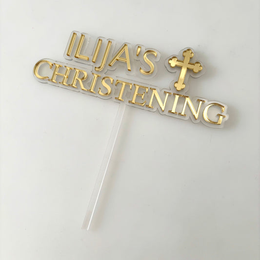 Gold christening cake topper with  personalised text and cross on a white background