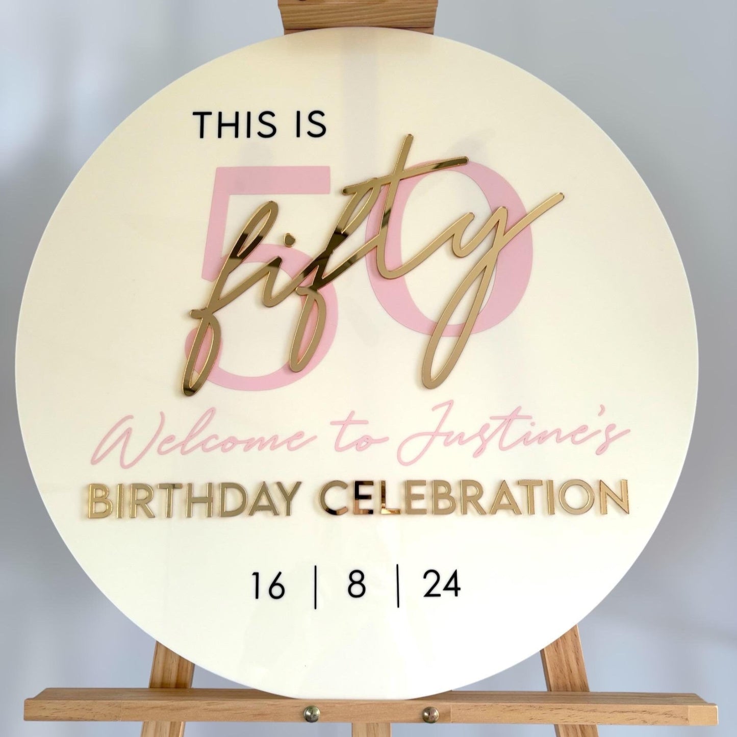 60cm Round sign with 'This is fifty, welcome to Justine's birthday celebration' text on a wooden stand.