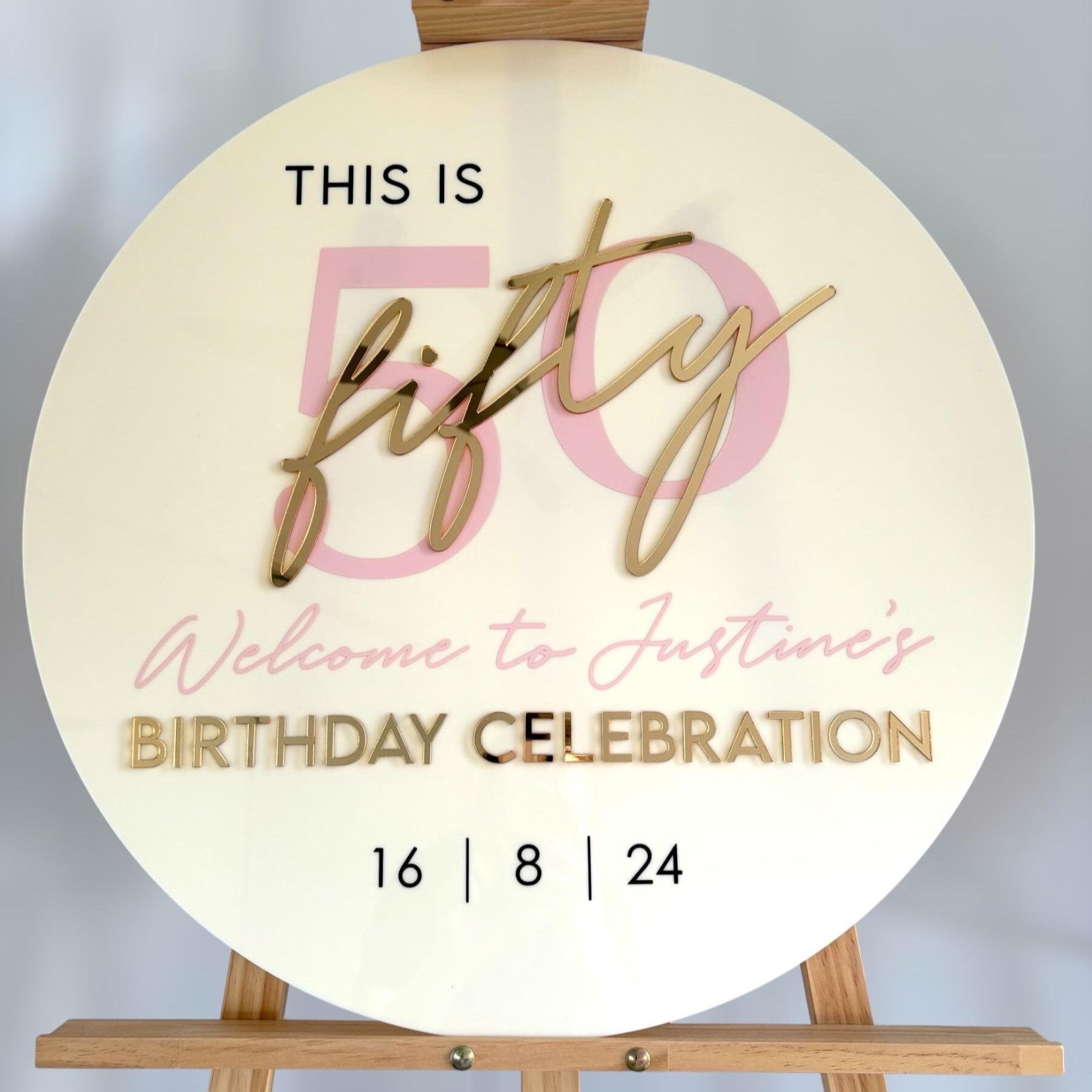 60cm Round sign with 'This is fifty, welcome to Justine's birthday celebration' text on a wooden stand.