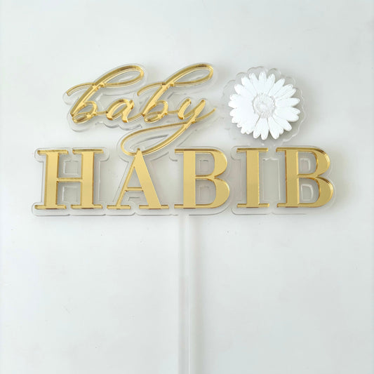 Gold personalised baby shower cake topper with a white flower.
