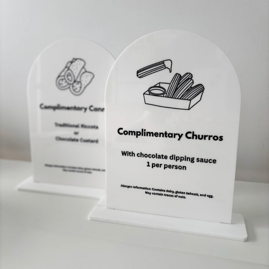 Two white acrylic signs with black text and illustrations on a light gray background