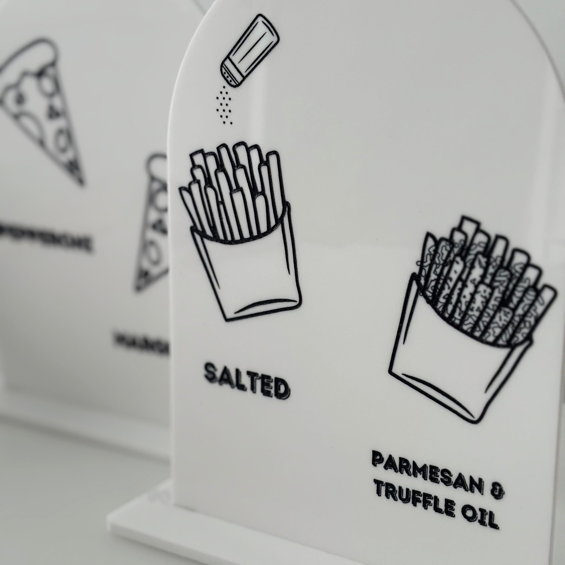 White salt and pepper shakers with black illustrations and text on a light gray background