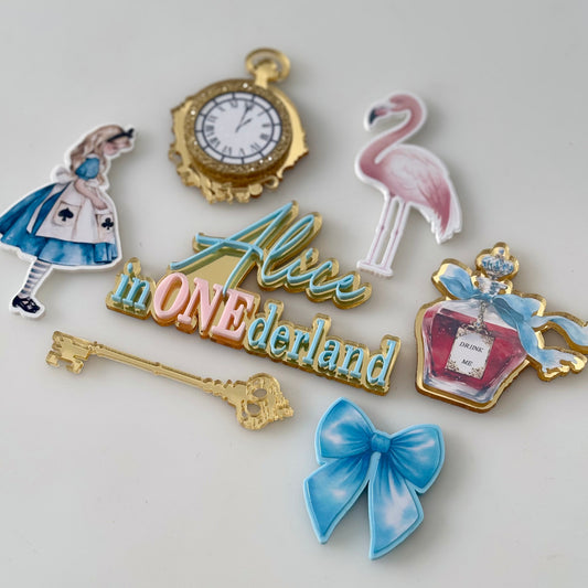 Set of decorative cake froppers with 'Alice in ONEderland' theme on a light grey background