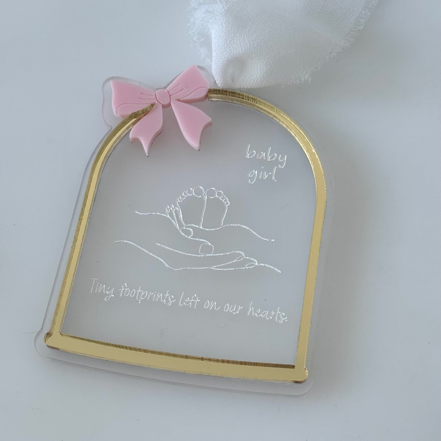 Decorative plaque with gold border, pink bow, and text on a white background