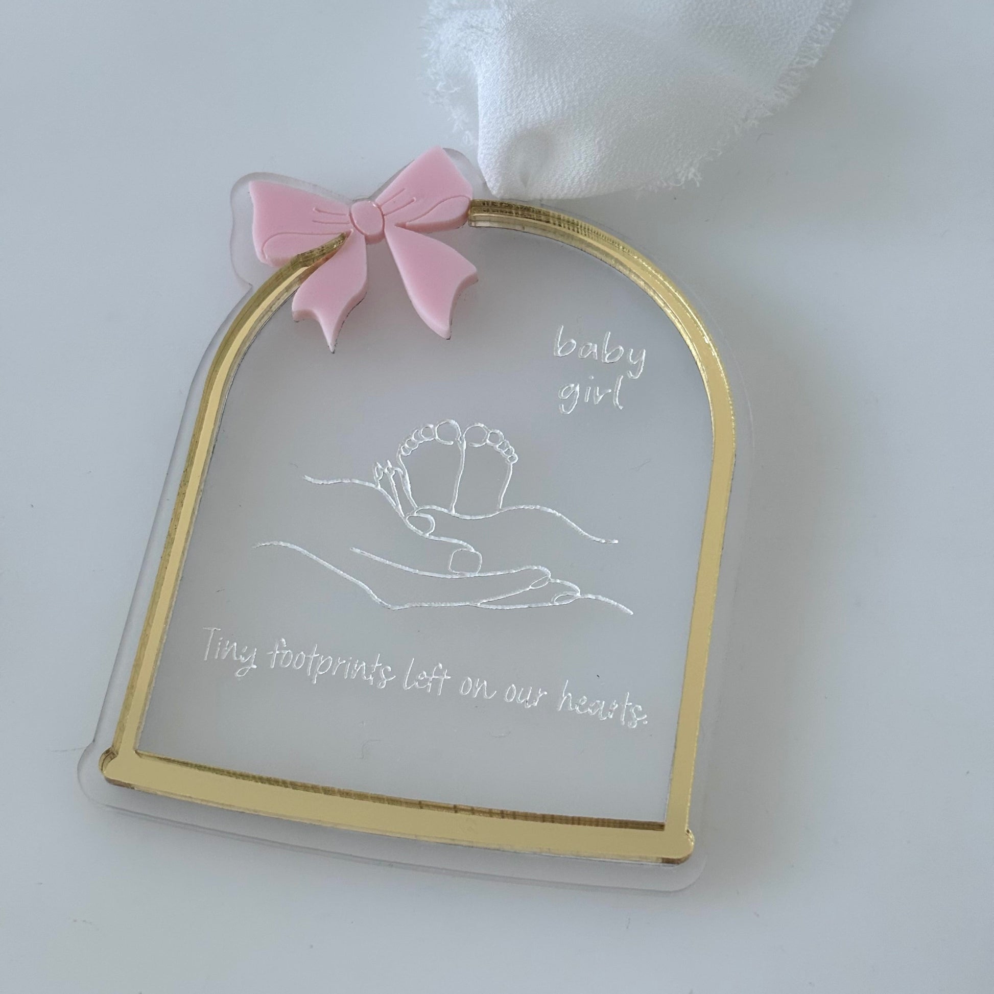 Decorative plaque with gold border, pink bow, and text on a white background