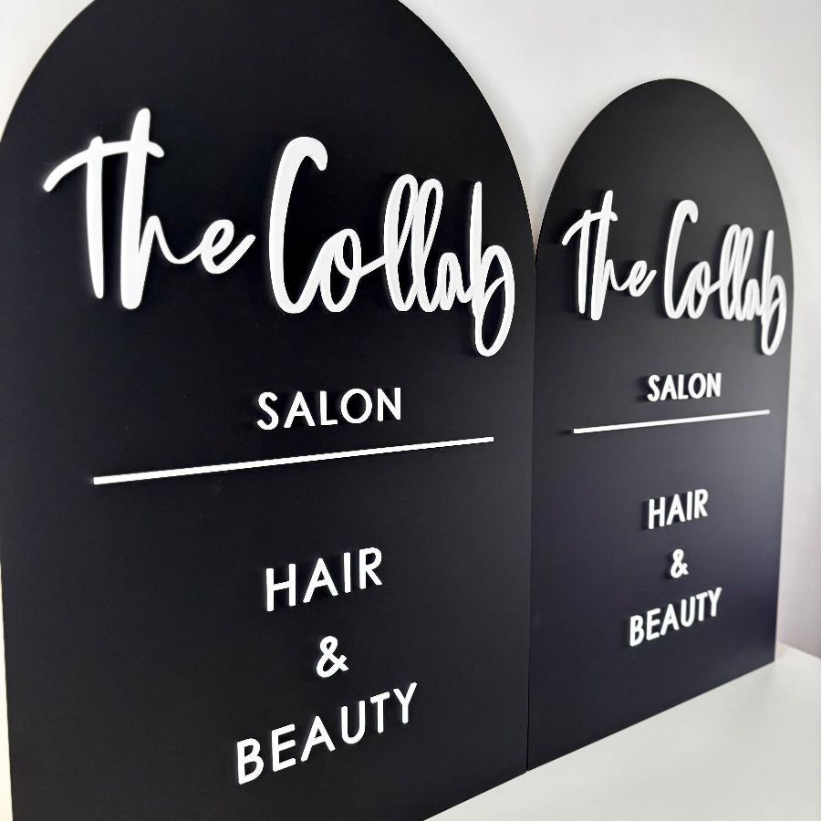 Two black signs with 'The Collab Salon' branding on a white background