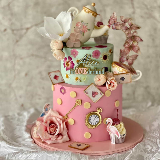 Alice In Wonderland Decorative cake with floral elements and a teapot on a textured surface