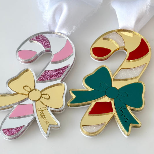 Two candy cane-shaped pins with bows on a white background