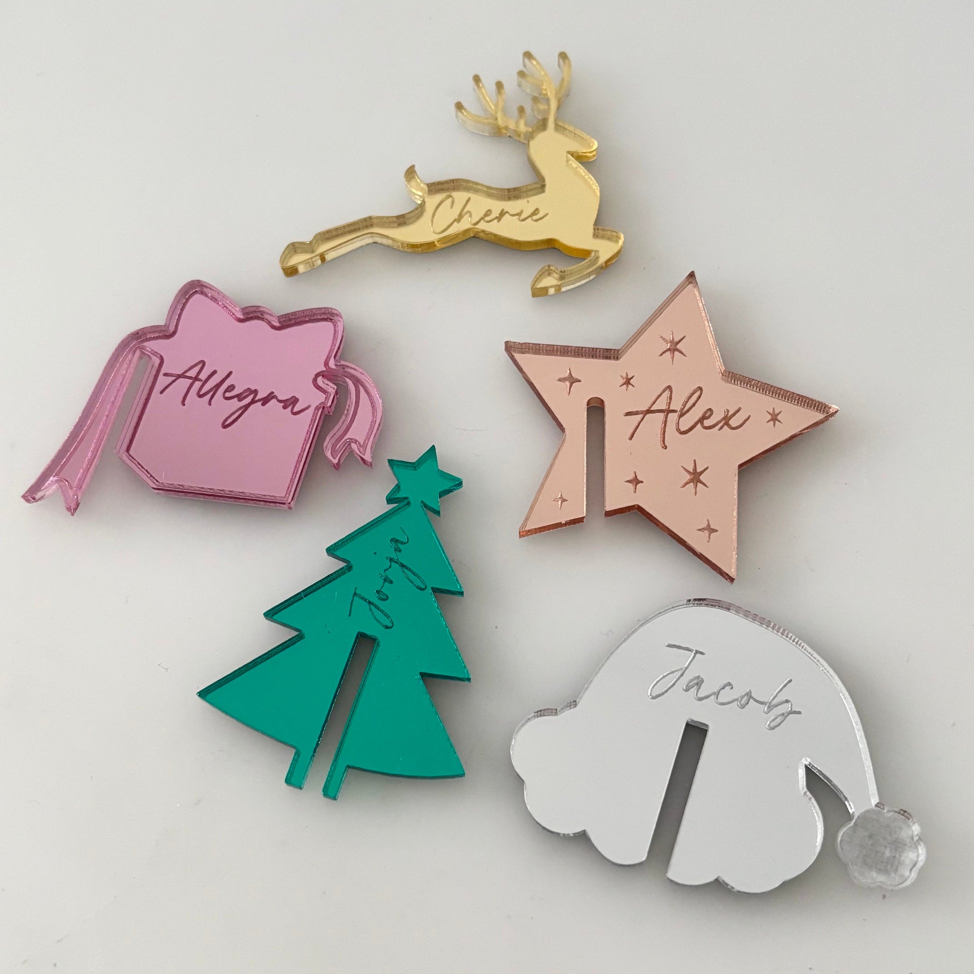 Set of personalized name drink tags in various shapes and colors on a light gray background