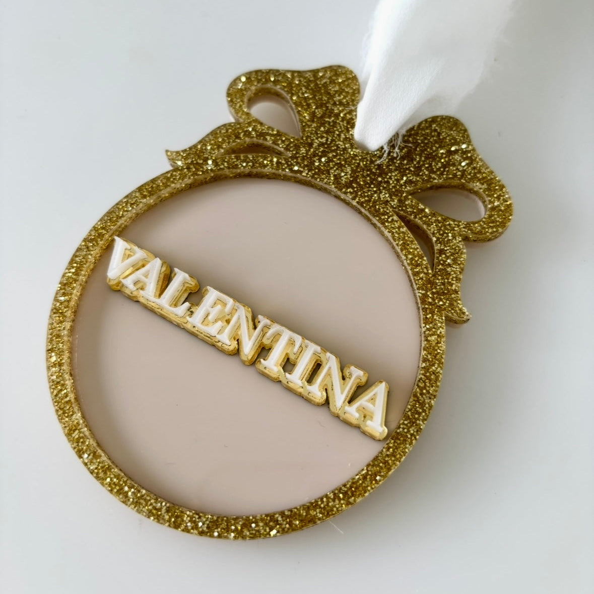 Gold glittery bauble with 'VALENTINA' text on a white background