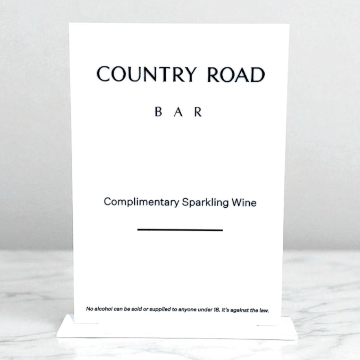 White A4 Sign with 'Country Road Bar' text on a marble surface