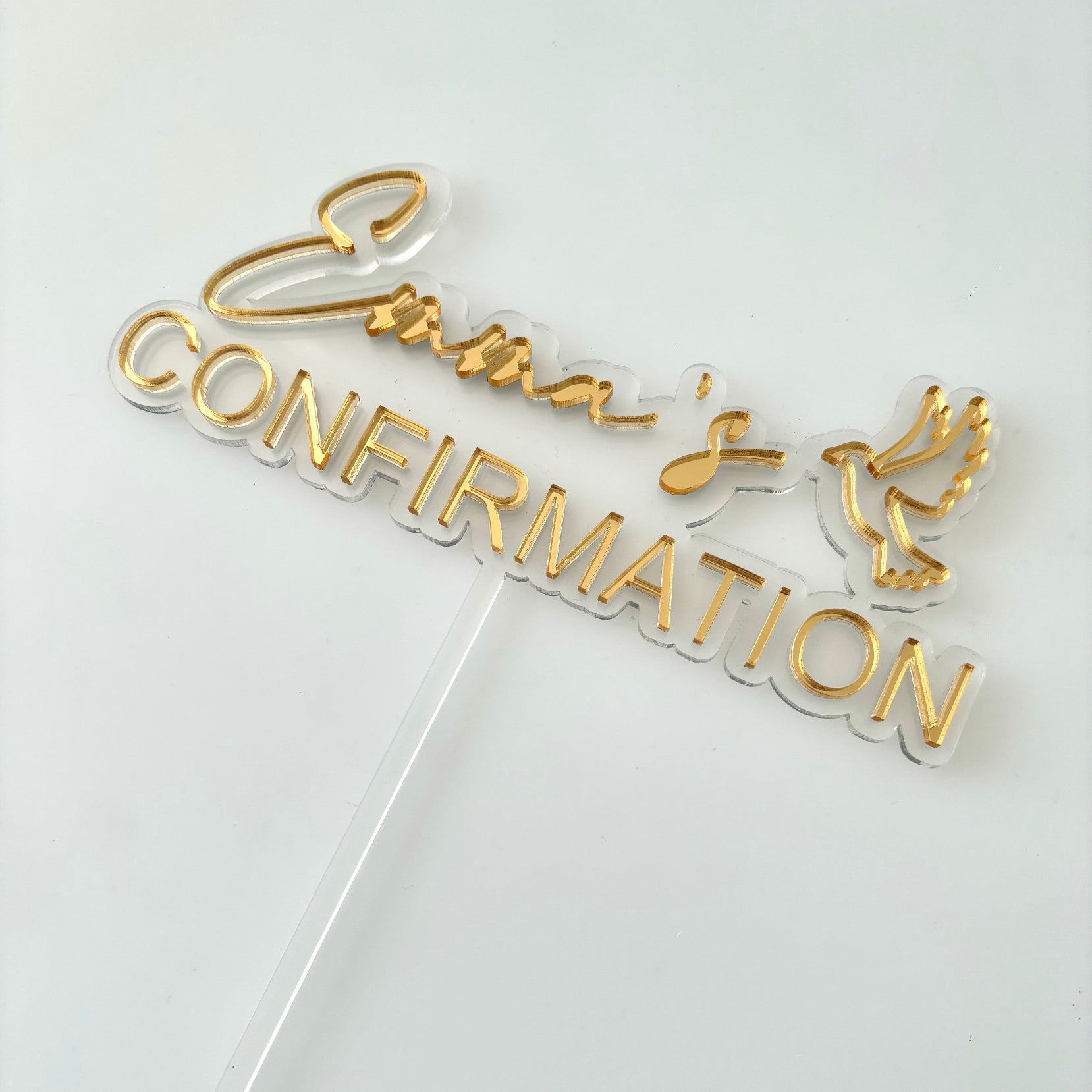 Gold 'Confirmation' cake topper on a white background