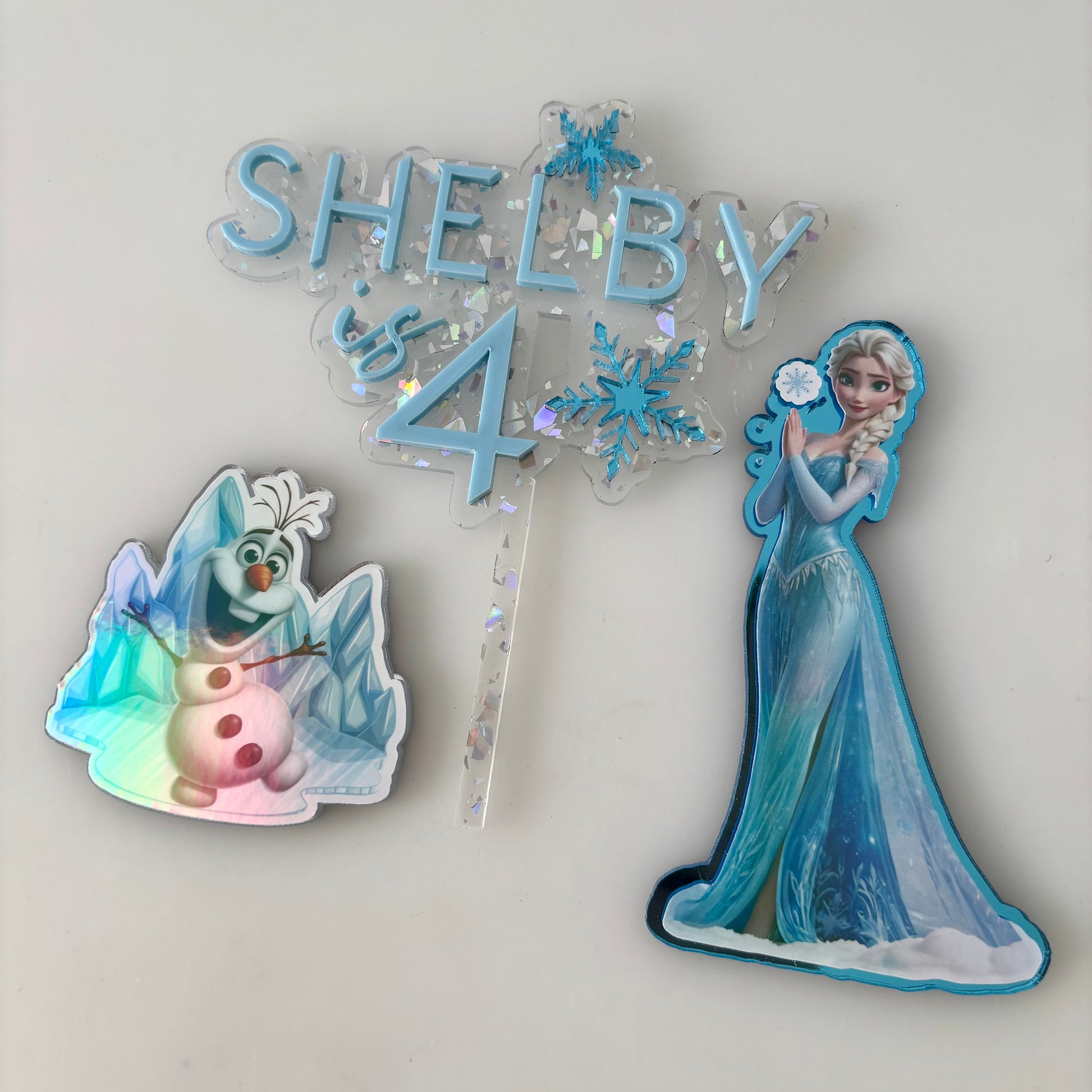 Frozen-themed birthday decorations with 'SHELBY 4' on a light gray background