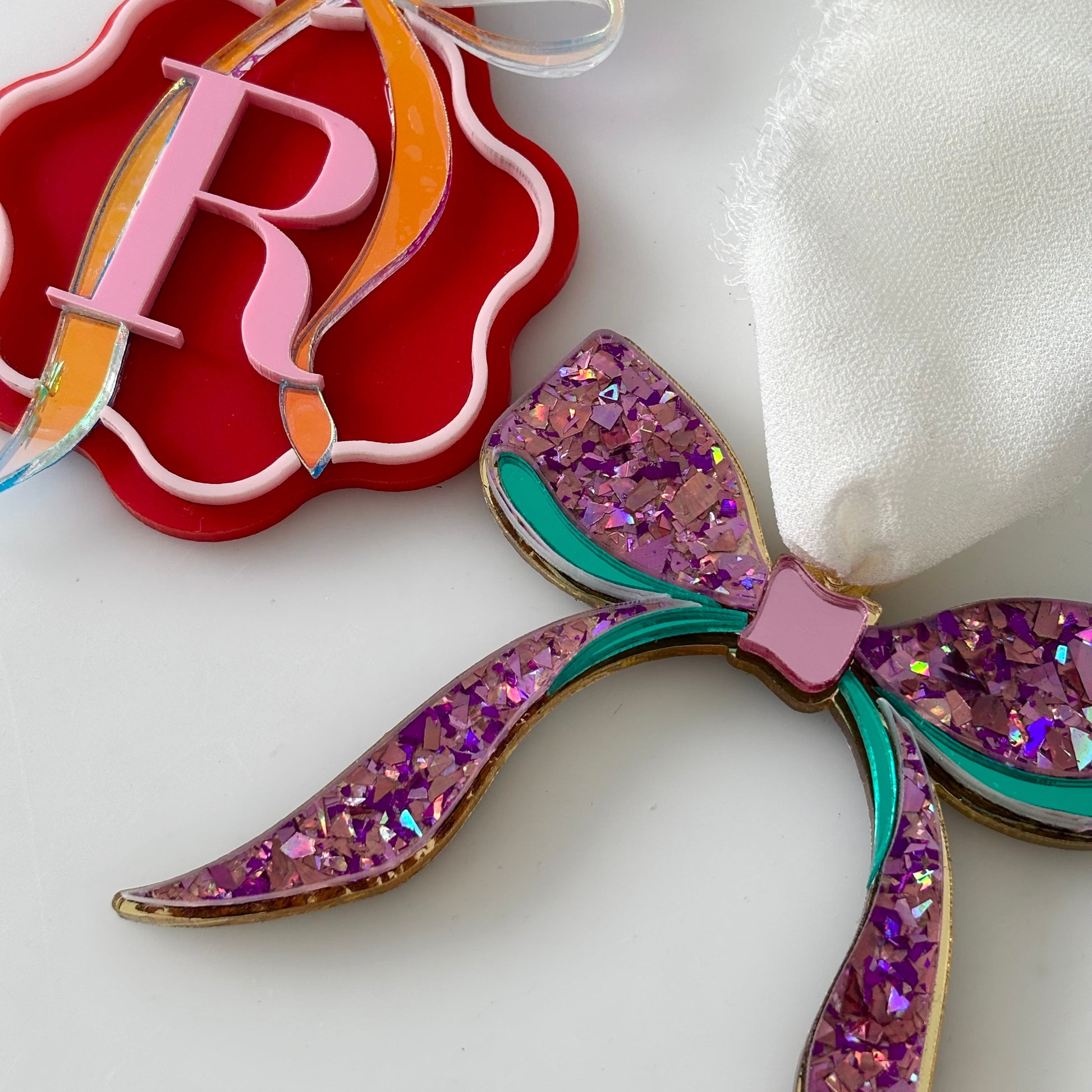Decorative bow with glittery purple and teal design on a white background