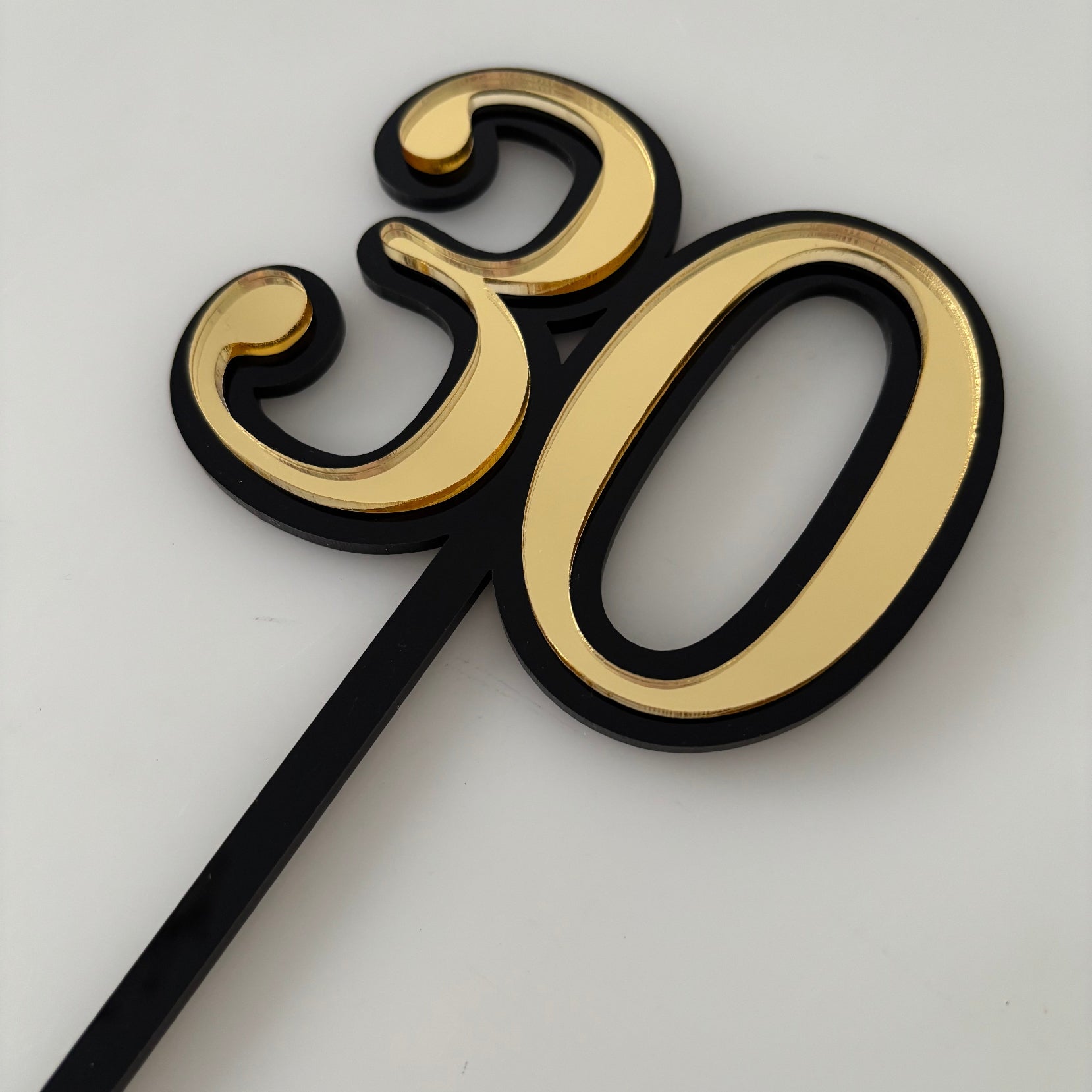 Gold cake topper with number '30' on a cake against a textured wall background