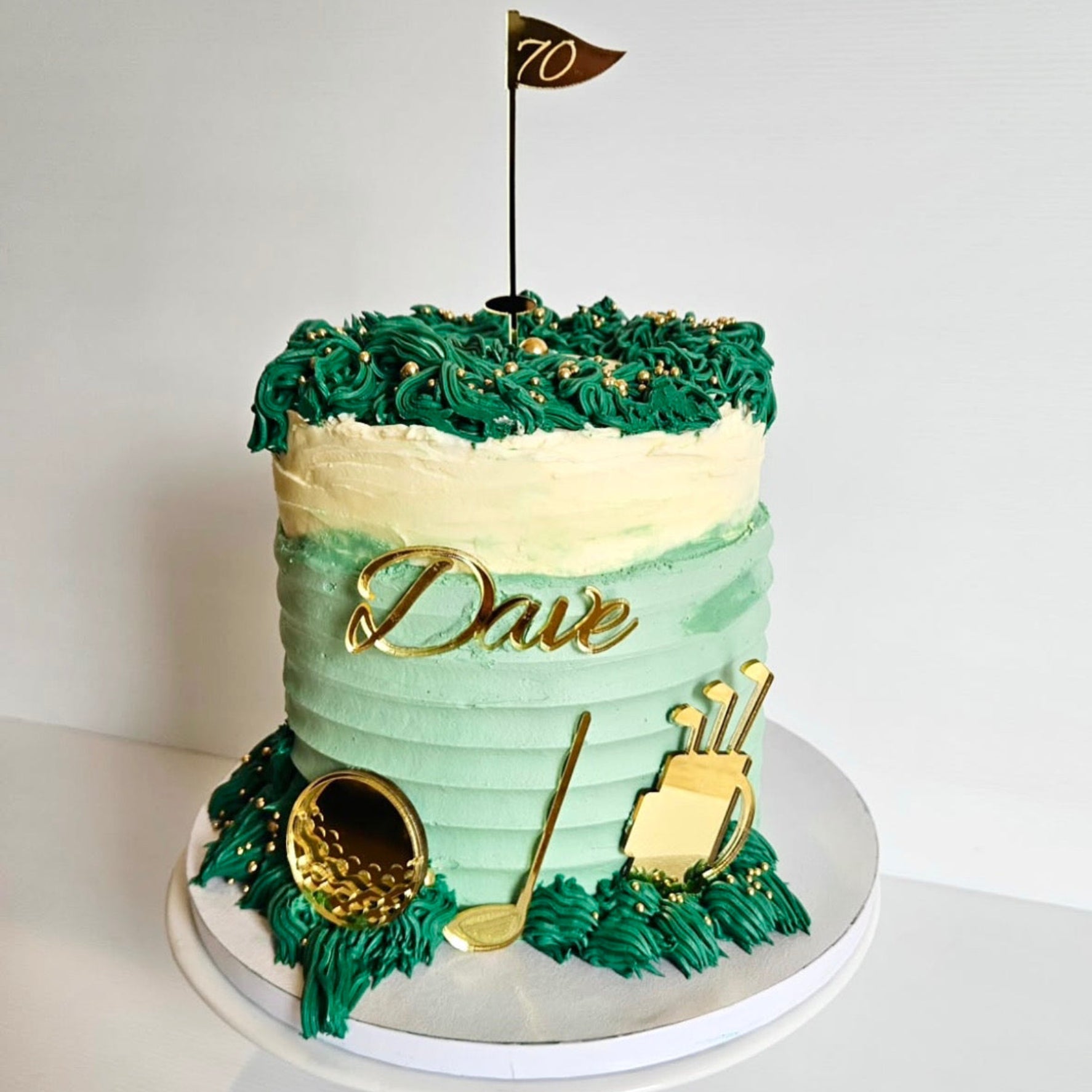 Golf-themed birthday cake with gold cake topper set on a white background