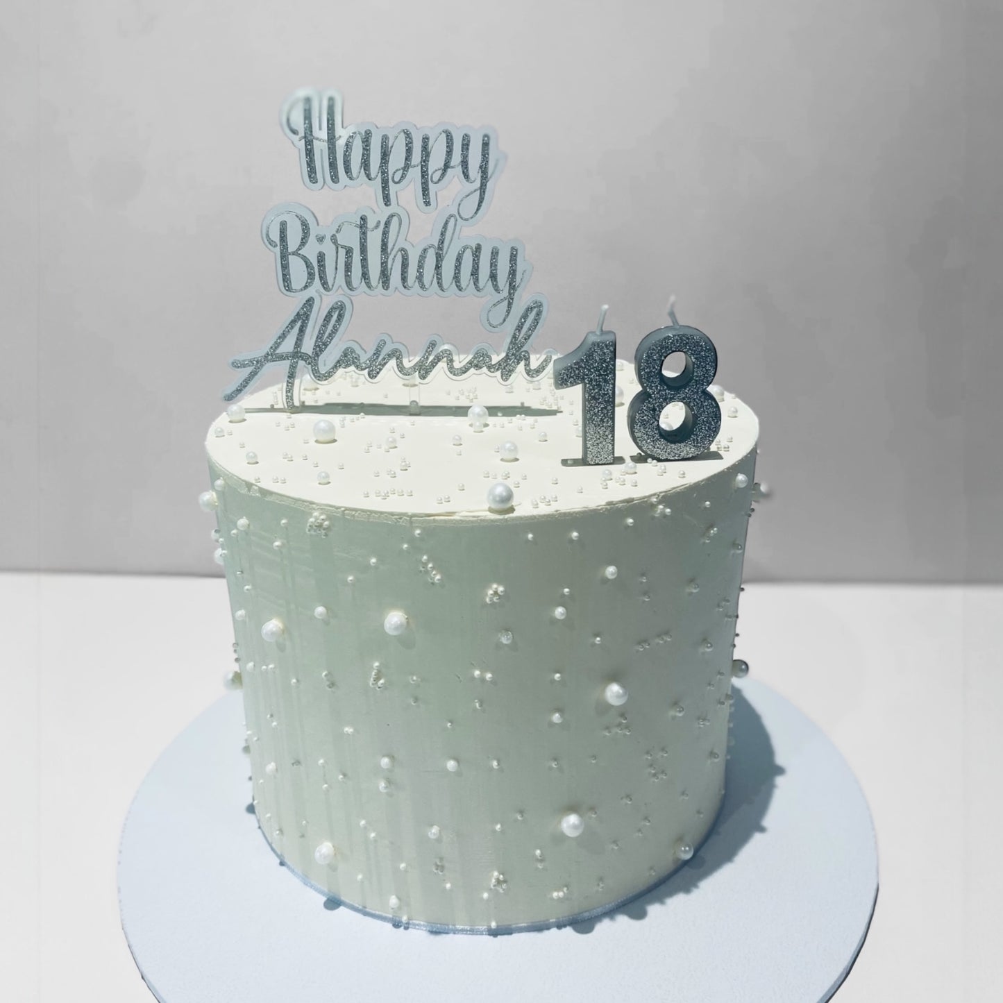birthday cake topper with 'Happy Birthday Alannah 18' topper on a gray background