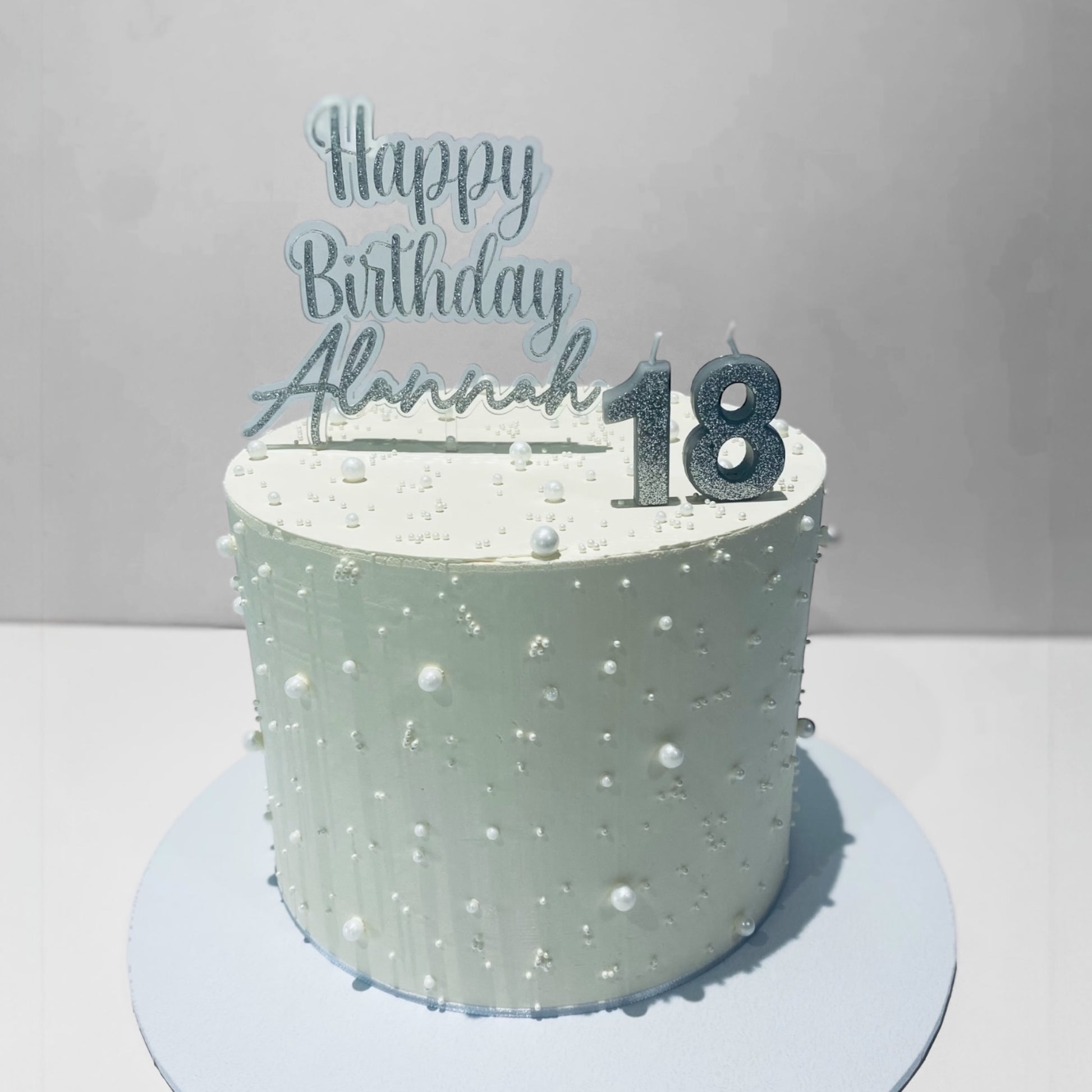 birthday cake topper with 'Happy Birthday Alannah 18' topper on a gray background