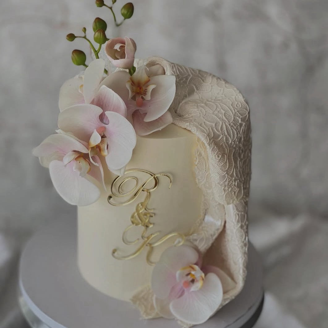 Decorative cake with floral elements and a monogram on a neutral background
