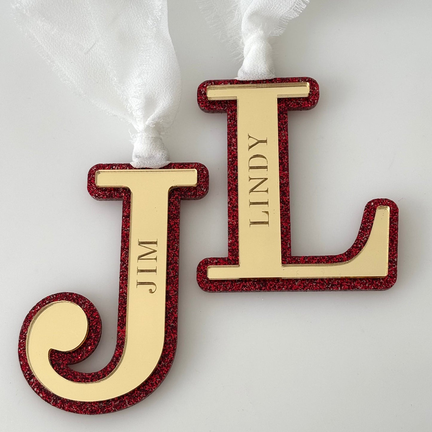 Two gold and red letter decorations with names on a white background