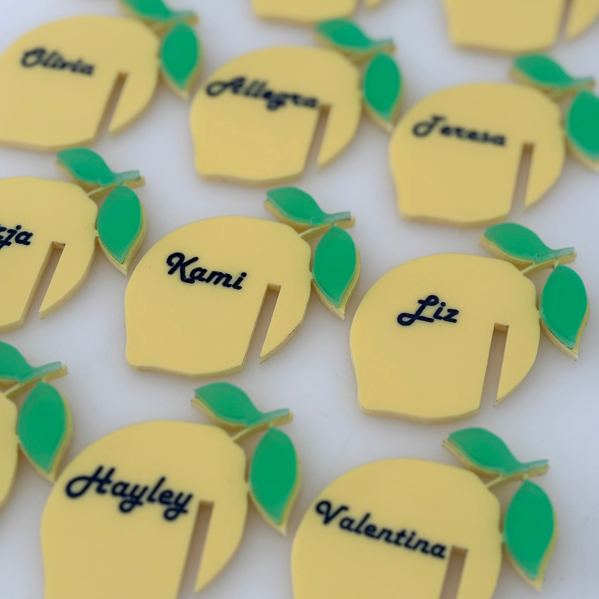 Yellow lemon-shaped drink name tags with green leaves on a white background