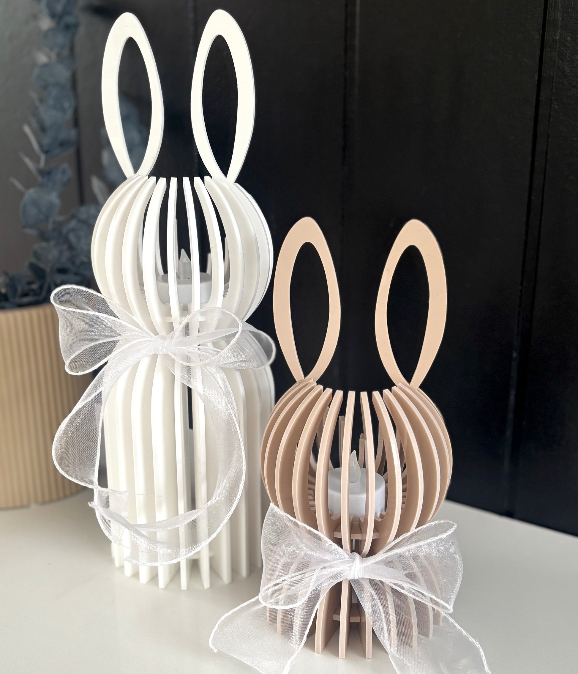 Two decorative bunny-shaped lanterns, one white and one brown, on a plain background.