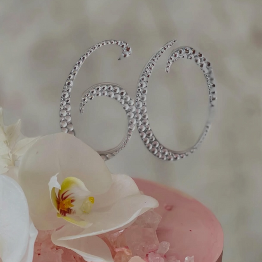 Silver number '60' on a cake with white orchids