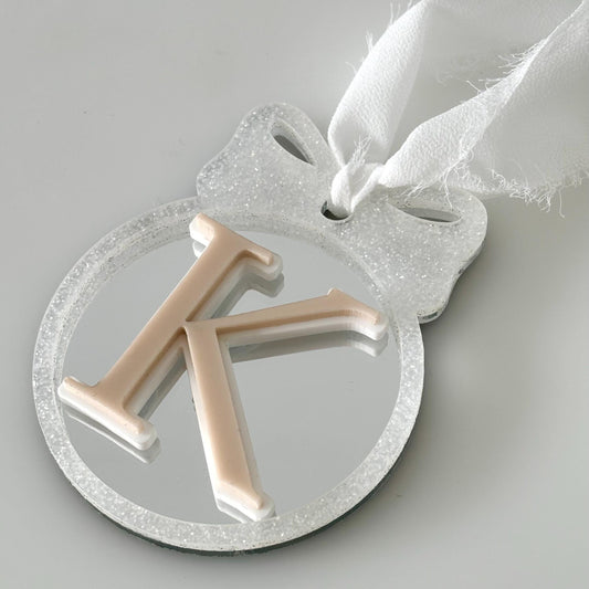 Decorative Christmas bauble with letter 'K' on a light gray background