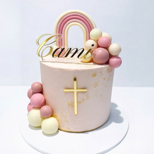 Decorative cake with pink and gold name & cross on a white background