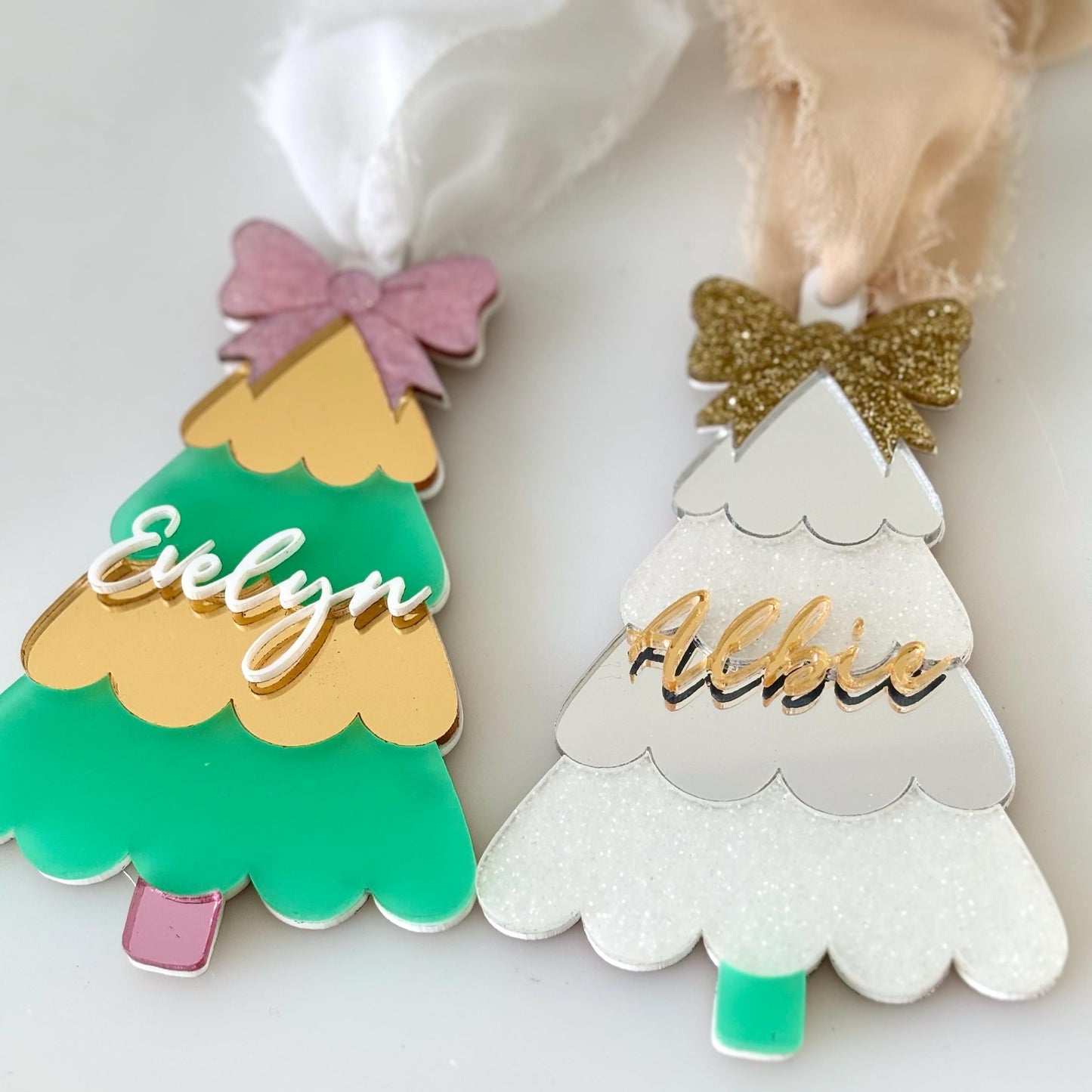 Two Christmas tree-shaped ornaments with names 'Evelyn' and 'Albie' on a white background.