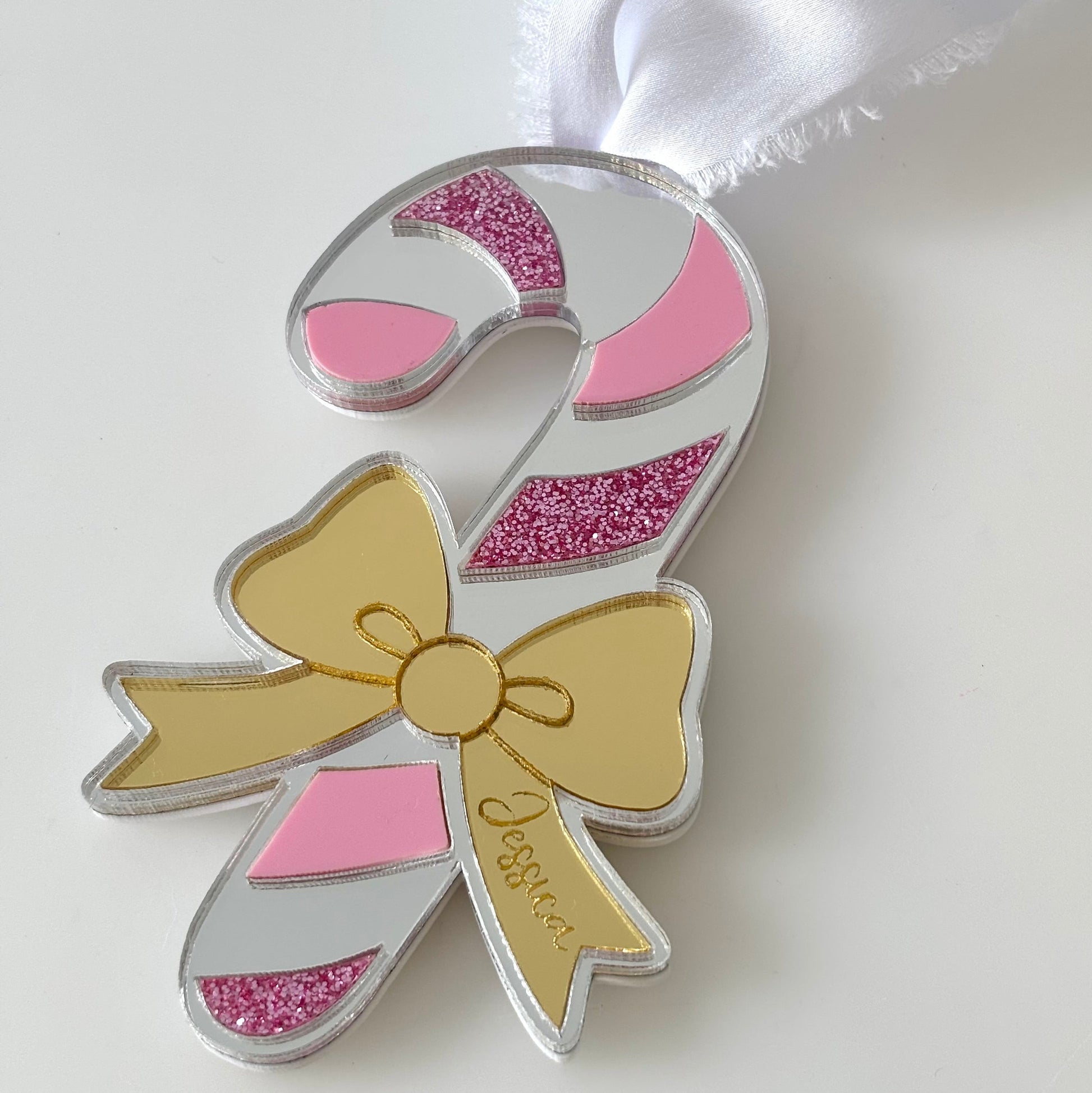 Decorative candy cane ornament with pink and silver details on a white background