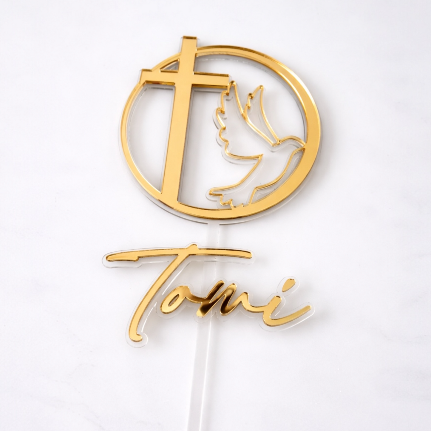 Gold cake topper with cross and dove design on a white background