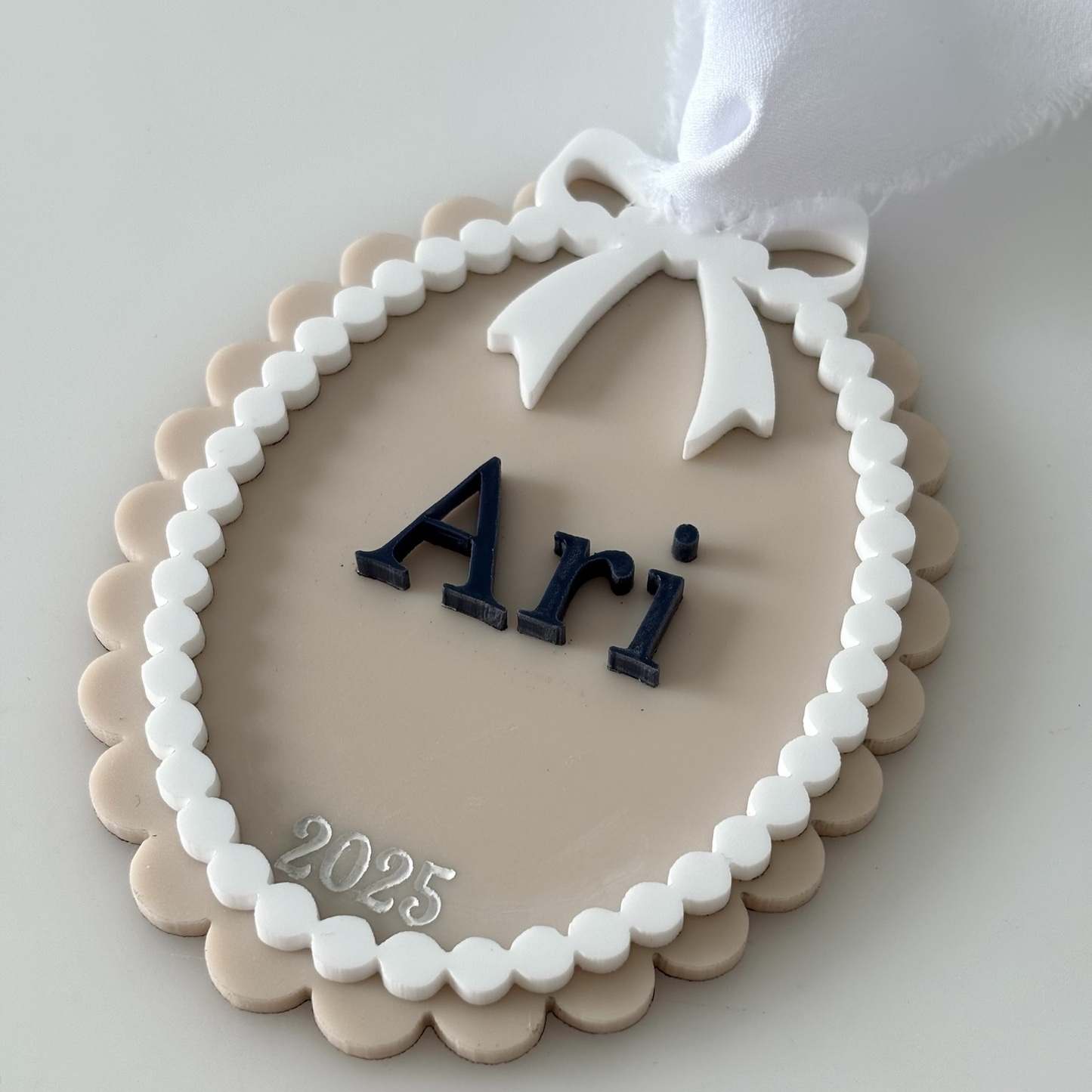 Decorative ornament with 'Ari' and '2025' on a white background